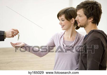Close-up of a real estate agent's hand handing over the keys to a couple View Large Photo Image Stock Photo - Close-up of a real estate agent's hand handing over the keys to a couple. Fotosearch