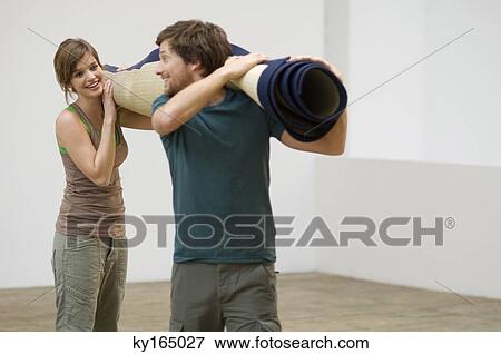 Couple carrying a carpet and smiling View Large Photo Image Stock Photo - Couple carrying a carpet and smiling. Fotosearch