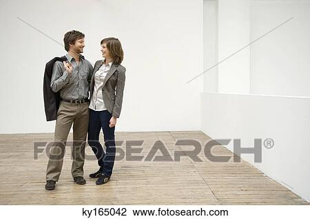Couple standing with their arms around each other in their new house and smiling View Large Photo Image Stock Image - Couple standing with their arms around each other in their new house and smiling. Fotosearch