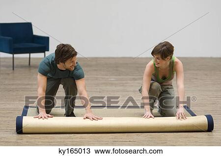 Couple unrolling a carpet on a hardwood floor View Large Photo Image Stock Image - Couple unrolling a carpet on a hardwood floor. Fotosearch
