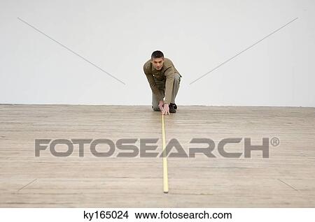 Picture - Interior designer measuring the hardwood floor with a tape measure. Fotosearch
