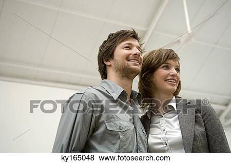 Low angle view of a mid adult man and a young woman looking away and smiling View Large Photo Image Stock Photo - Low angle view of a mid adult man and a young woman looking away and smiling. Fotosearch
