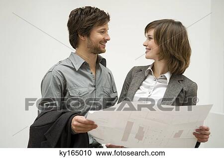 Mid adult man and a young woman holding a blueprint and looking at each other View Large Photo Image Stock Image - Mid adult man and a young woman holding a blueprint and looking at each other. Fotosearch