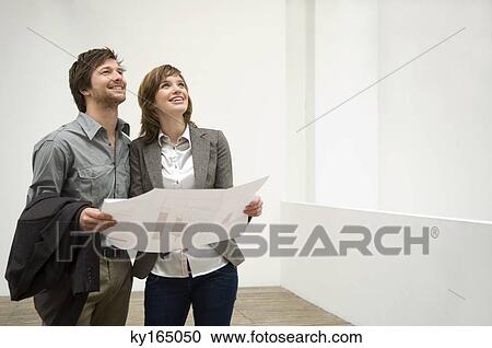 Mid adult man and a young woman holding a blueprint View Large Photo Image Stock Image - Mid adult man and a young woman holding a blueprint. Fotosearch