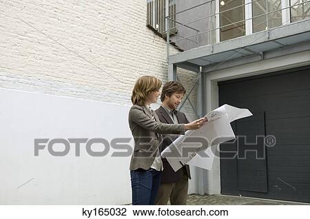 Mid adult man and a young woman looking at a blueprint View Large Photo Image Stock Image - Mid adult man and a young woman looking at a blueprint. Fotosearch
