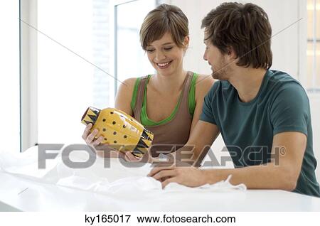 Stock Photo - Mid adult man and a young woman looking at a vase. Fotosearch