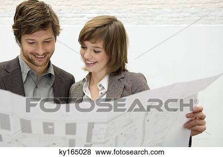 Mid adult man and a young woman looking at a blueprint View Large Photo Image Stock Photo - Mid adult man and a young woman looking at a blueprint. Fotosearch