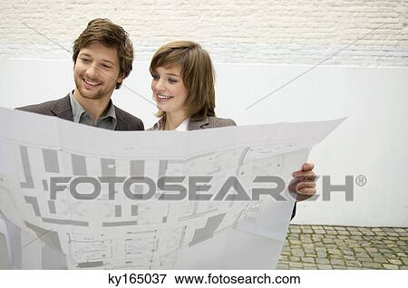 Mid adult man and a young woman looking at a blueprint View Large Photo Image Stock Photo - Mid adult man and a young woman looking at a blueprint. Fotosearch