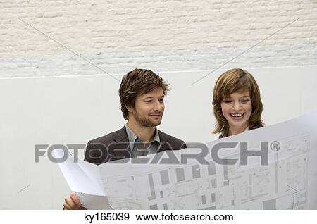 Mid adult man and a young woman looking at a blueprint View Large Photo Image Stock Photo - Mid adult man and a young woman looking at a blueprint. Fotosearch