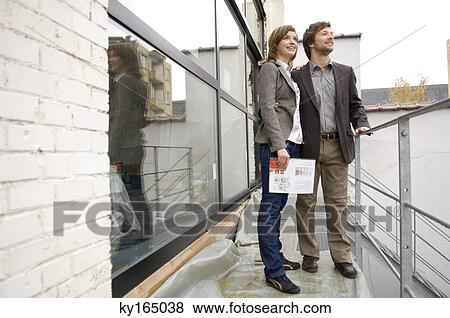 Mid adult man and a young woman standing at a balcony View Large Photo Image Stock Photo - Mid adult man and a young woman standing at a balcony. Fotosearch
