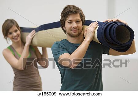 Stock Photo - Portrait of a couple carrying a carpet. Fotosearch