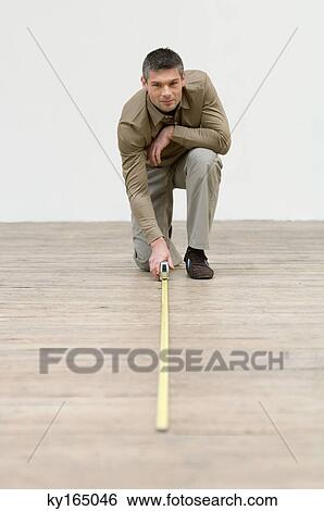 Portrait of an interior designer measuring hardwood floor with a tape measure View Large Photo Image Stock Photograph - Portrait of an interior designer measuring hardwood floor with a tape measure. Fotosearch