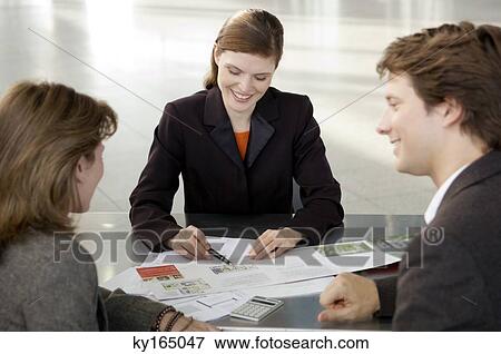 Real estate agent explaining to a couple View Large Photo Image Stock Photo - Real estate agent explaining to a couple. Fotosearch