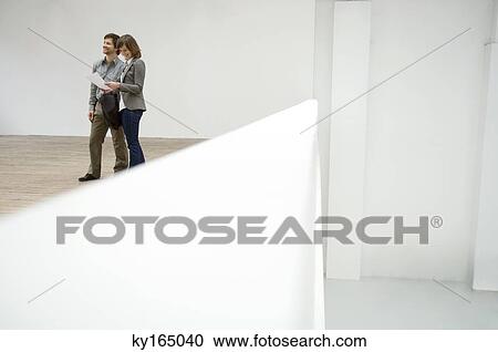 Young woman looking at a blueprint and a mid adult man standing beside her View Large Photo Image Stock Image - Young woman looking at a blueprint and a mid adult man standing beside her. Fotosearch
