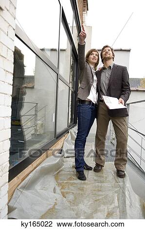 Young woman pointing forward and a mid adult man standing beside her View Large Photo Image Stock Image - Young woman pointing forward and a mid adult man standing beside her. Fotosearch