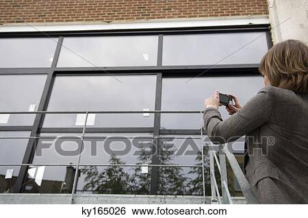 Young woman taking a picture of a house with a digital camera View Large Photo Image Stock Photograph - Young woman taking a picture of a house with a digital camera. Fotosearch