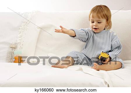 Baby boy sitting on a couch and playing with toys View Large Photo Image Stock Image - Baby boy sitting on a couch and playing with toys. Fotosearch