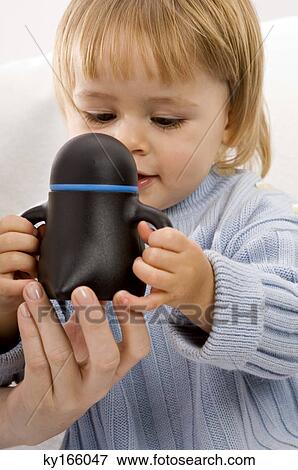 Close-up of a baby boy holding a baby cup View Large Photo Image Stock Photo - Close-up of a baby boy holding a baby cup. Fotosearch