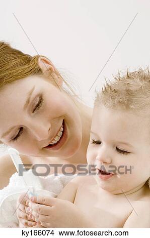 Close-up of a baby boy holding a comb and sitting with his mother View Large Photo Image Picture - Close-up of a baby boy holding a comb and sitting with his mother. Fotosearch