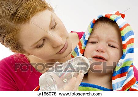 Close-up of a young woman feeding from a baby bottle to her crying son View Large Photo Image Stock Photo - Close-up of a young woman feeding from a baby bottle to her crying son. Fotosearch
