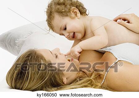 Close-up of a young woman lying and playing with her son View Large Photo Image Stock Image - Close-up of a young woman lying and playing with her son. Fotosearch
