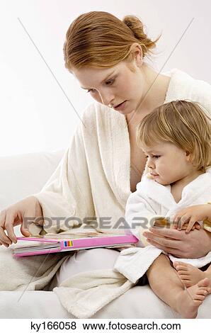 Close-up of a young woman sitting with her baby boy and looking at a picture book View Large Photo Image Stock Photo - Close-up of a young woman sitting with her baby boy and looking at a picture book. Fotosearch