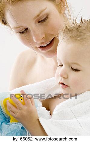 Close-up of a young woman wrapping her son in a towel and smiling View Large Photo Image Stock Image - Close-up of a young woman wrapping her son in a towel and smiling. Fotosearch