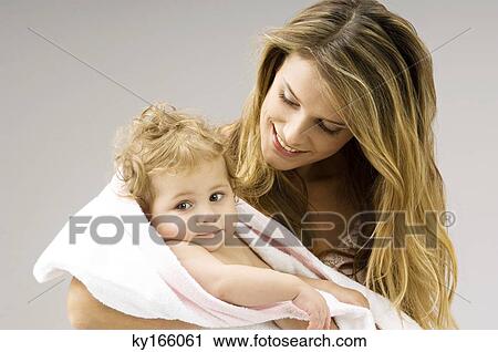 Close-up of a young woman wrapping her son in a towel and smiling View Large Photo Image Stock Image - Close-up of a young woman wrapping her son in a towel and smiling. Fotosearch