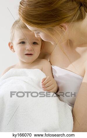 Stock Image - Close-up of a young woman wrapping her son in a towel. Fotosearch