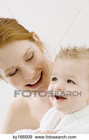 Stock Photo - Close-up of a young woman wrapping her son in a towel and smiling. Fotosearch