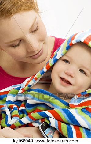 Close-up of a young woman wrapping her son in a towel and smiling View Large Photo Image Stock Photo - Close-up of a young woman wrapping her son in a towel and smiling. Fotosearch