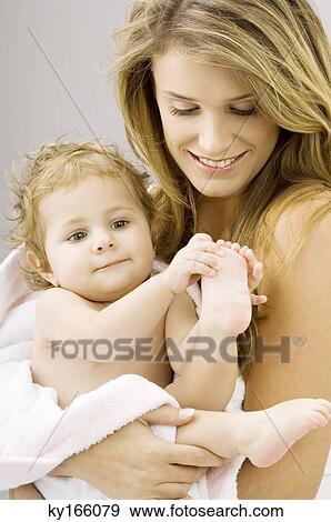 Close-up of a young woman wrapping her son in a towel and smiling View Large Photo Image Stock Photo - Close-up of a young woman wrapping her son in a towel and smiling. Fotosearch