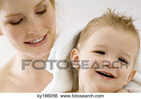 Stock Photograph - Close-up of a young woman wrapping her son in a towel and smiling. Fotosearch