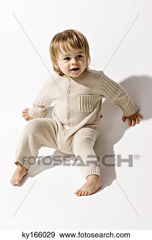 High angle view of a baby boy sitting on the floor and smiling View Large Photo Image Stock Photo - High angle view of a baby boy sitting on the floor and smiling. Fotosearch