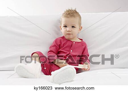 Portrait of a baby boy sitting on a couch and holding a brush View Large Photo Image Stock Image - Portrait of a baby boy sitting on a couch and holding a brush. Fotosearch
