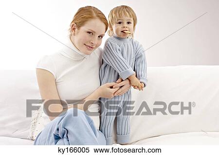Stock Photography - Portrait of a young woman sitting on a couch with her son. Fotosearch