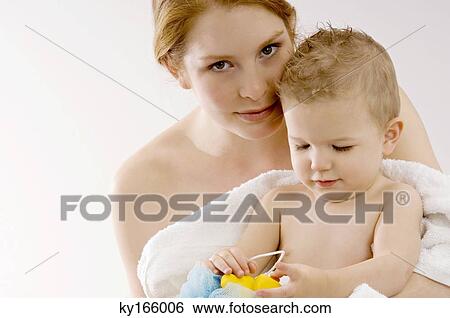 Portrait of a young woman wrapping her son in a towel and smiling View Large Photo Image Stock Photograph - Portrait of a young woman wrapping her son in a towel and smiling. Fotosearch