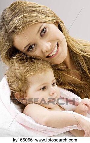 Portrait of a young woman wrapping her son in a towel and smiling View Large Photo Image Stock Photograph - Portrait of a young woman wrapping her son in a towel and smiling. Fotosearch