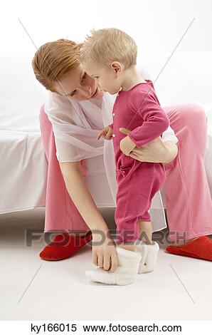Young woman putting baby booties to her son View Large Photo Image Stock Photography - Young woman putting baby booties to her son. Fotosearch
