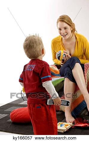 Stock Photo - Young woman sitting on a couch and playing with her son. Fotosearch