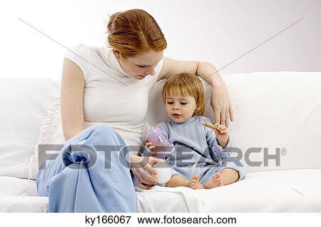 Young woman sitting on a couch and playing with her son View Large Photo Image Stock Photo - Young woman sitting on a couch and playing with her son. Fotosearch