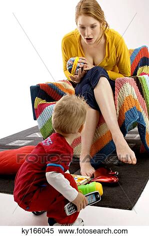 Young woman sitting on a couch and playing with her son View Large Photo Image Stock Photography - Young woman sitting on a couch and playing with her son. Fotosearch