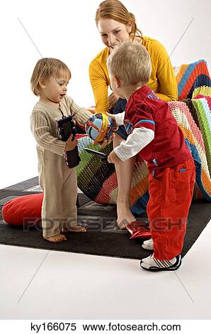 Stock Photography - Young woman sitting on a couch and playing with her two children. Fotosearch