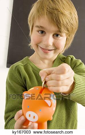 Boy putting a coin into a piggy bank View Large Photo Image Stock Image - Boy putting a coin into a piggy bank. Fotosearch
