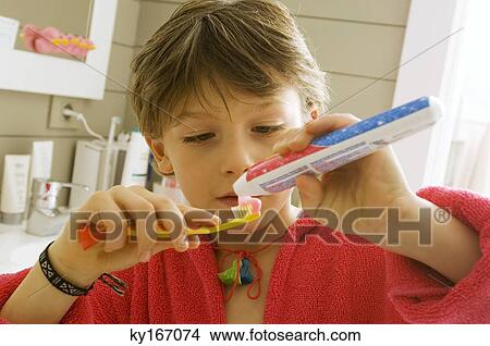 Picture - Close-up of a boy holding a toothpaste and a toothbrush. Fotosearch