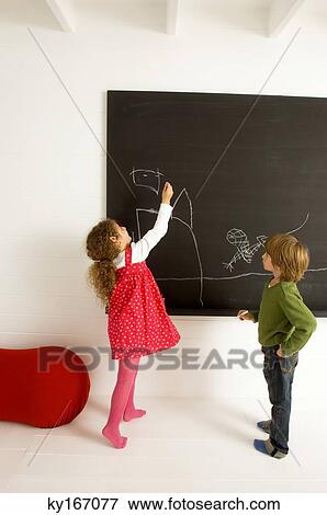Girl drawing on a blackboard and her brother watching her View Large Photo Image Stock Photo - Girl drawing on a blackboard and her brother watching her. Fotosearch