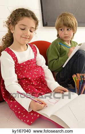 Girl drawing on a notepad and her brother looking at her View Large Photo Image Stock Image - Girl drawing on a notepad and her brother looking at her. Fotosearch