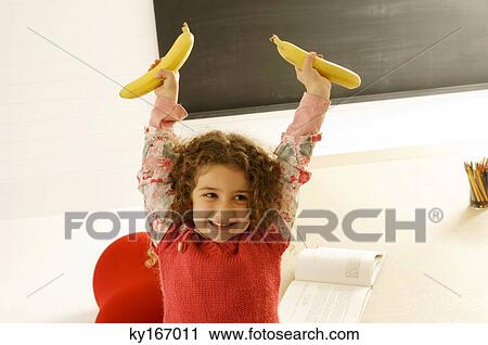 Stock Image - Girl holding two bananas. Fotosearch