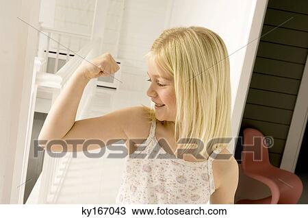 Stock Image - Girl looking at her bicep. Fotosearch