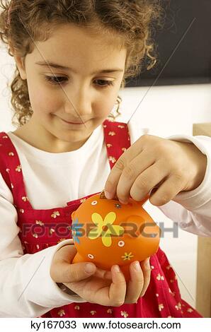 Girl putting a coin into a piggy bank View Large Photo Image Stock Image - Girl putting a coin into a piggy bank. Fotosearch